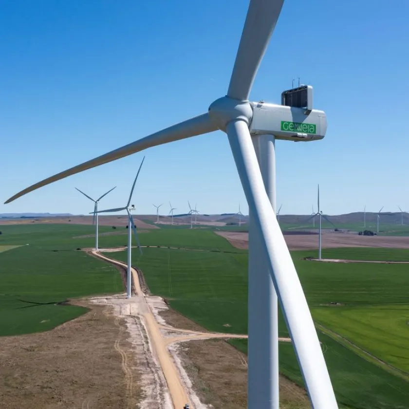 Wind turbine at the foreground and field of wind turbines in the background